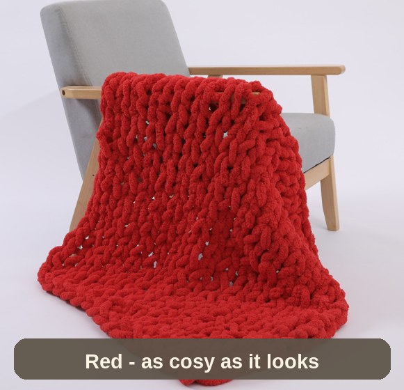 Red weighted blanket over an armchair, angled view - a statement piece that is as cosy as it looks.