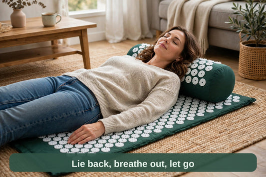 Woman lying back on the acupressure mat and pillow set at home, relaxed — lie back, breathe out, let go