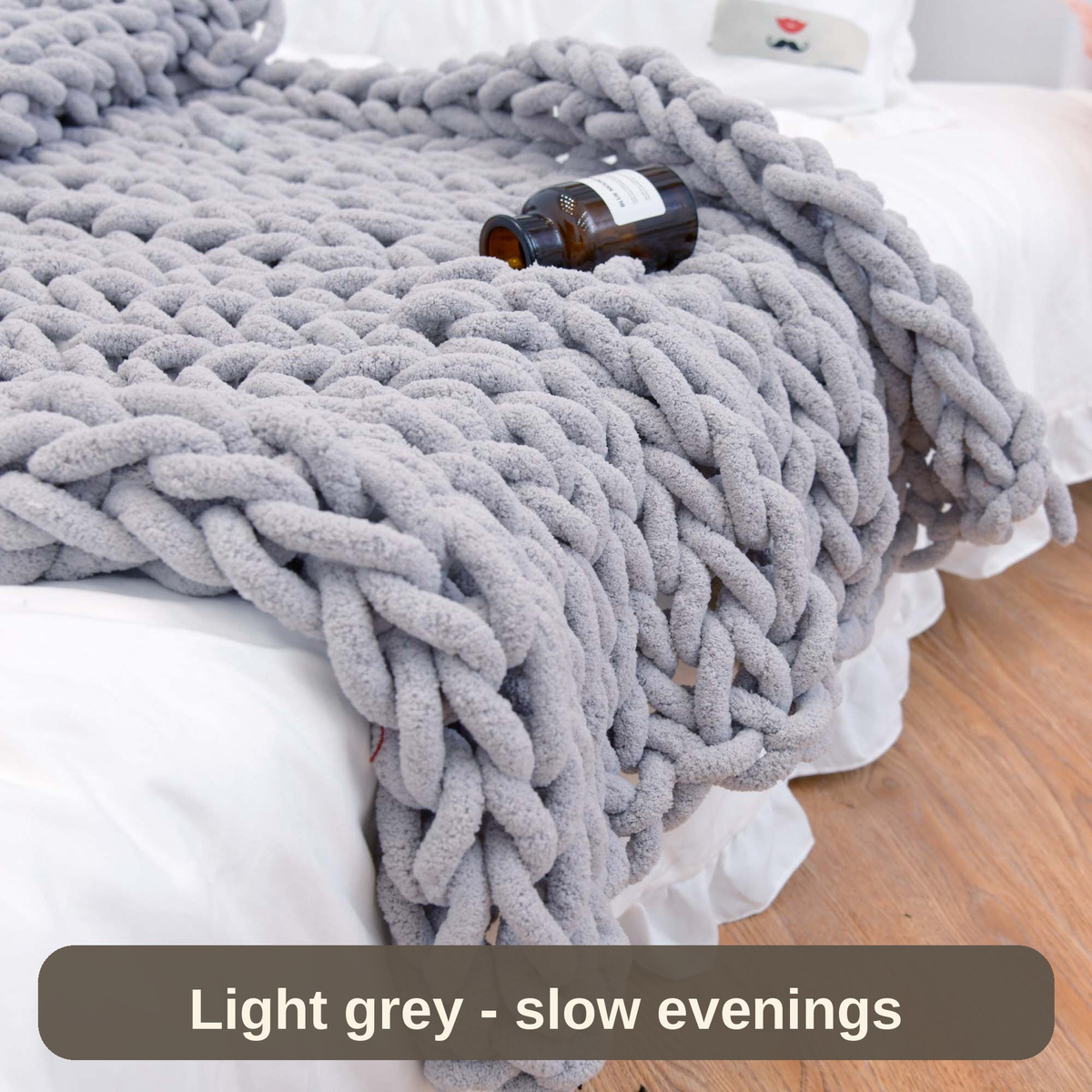 Light grey weighted blanket resting on the bed with a good book nearby - made for slow evenings.