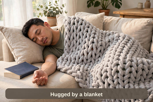 Man asleep on the sofa under the chunky knit weighted blanket — hugged by a blanket